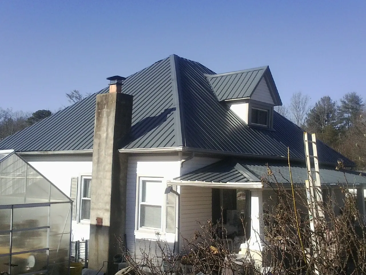 Dark blue standing seam metal roof on a white farmhouse with dormer — Slate & Tile Roof Repair by Roofing Brothers in Homestead