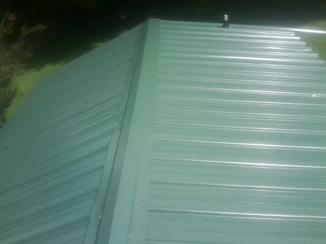 New green metal panels meeting at the ridge of a roof — Flat Roof Repair work by our crew in Homestead