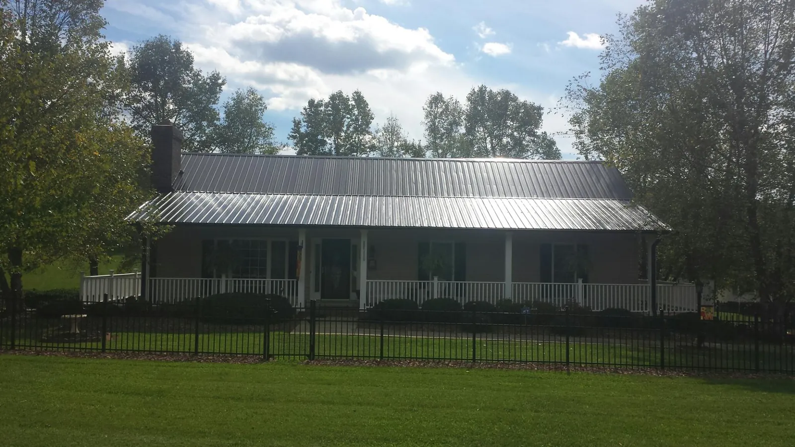 Gray metal roof on a brick ranch with a full width front porch — Gutter Guard Installation work by our crew in Homestead